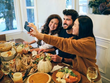 a group of friends celebrating thanksgiving dinner together in a home taking a selfie at the dinner table