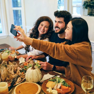 thanksgiving captions - a group of friends celebrating thanksgiving dinner together in a home taking a selfie at the dinner table a group of friends celebrating thanksgiving dinner together in a home taking a selfie at the dinner table