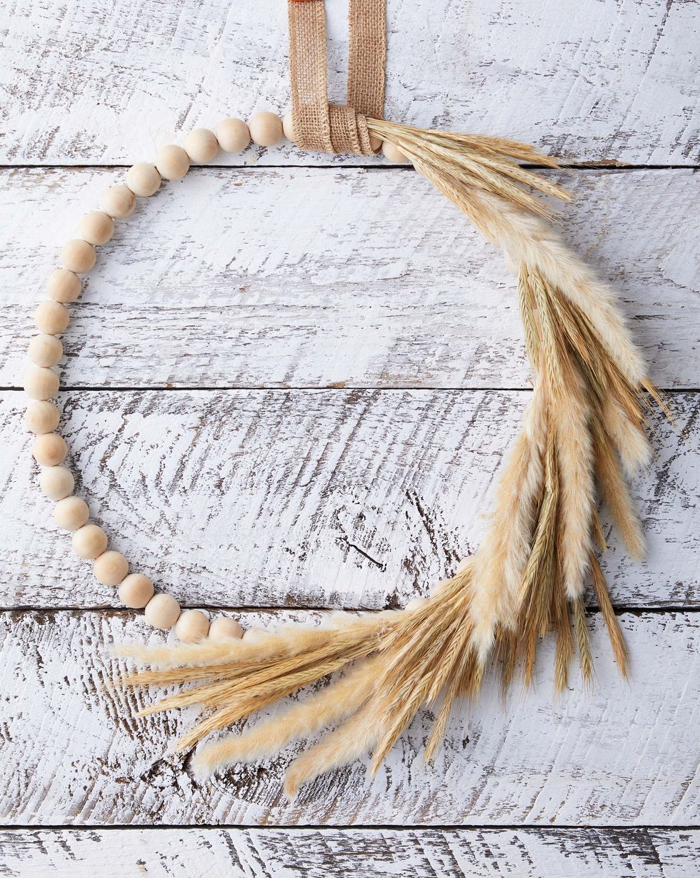 wreath made from craft beads and dried wheat and grass on a whitewashed background