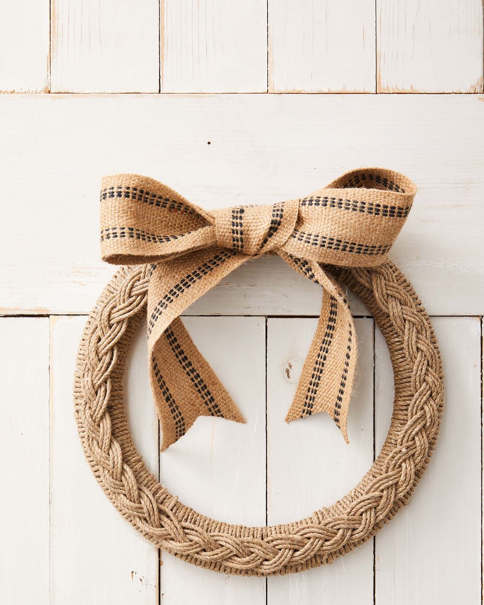 wreath form covered in rope topped with a barid made from the same rope all hung on a white door