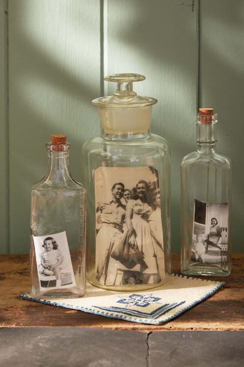 vintage photos nestled in antique glass bottle sitting on a wood table