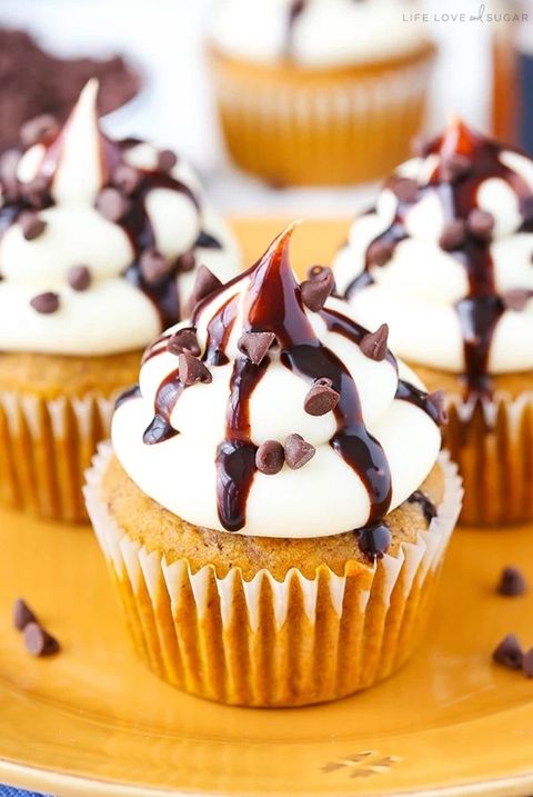pumpkin chocolate chip cupcakes with white frosting and chocolate sauce