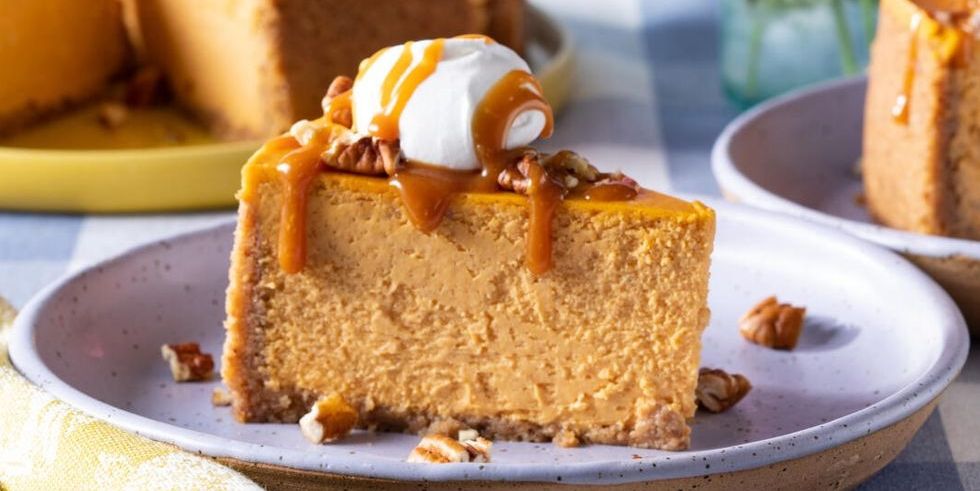 pumpkin cheesecake slice on plate with caramel and whipped cream
