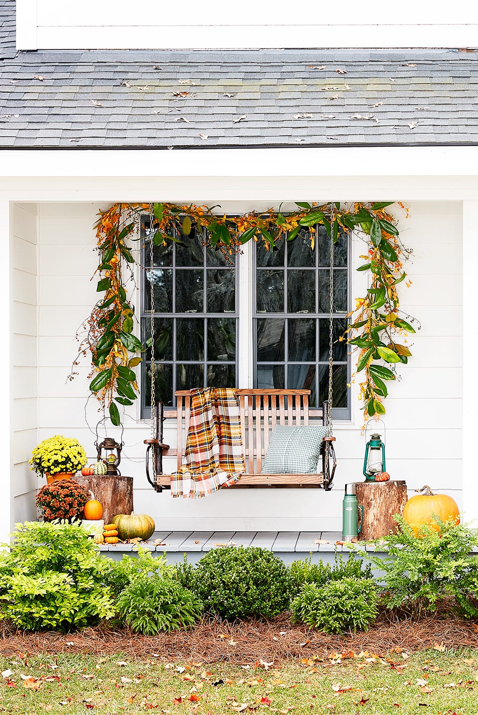 front porch with swing and orange door decorated for fall