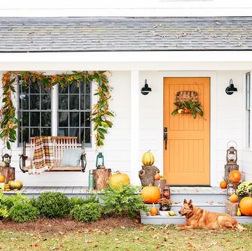 front porch with swing and orange door decorated for fall