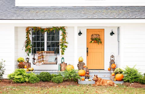 front porch with swing and orange door decorated for fall