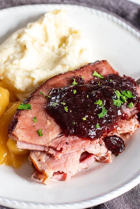 cranberry glazed ham sliced on plate with mashed potatoes