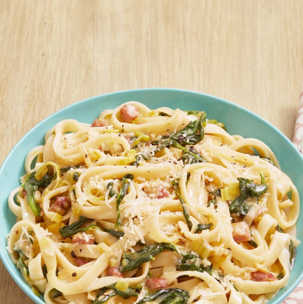 pasta with ham leeks and spinach on wood surface