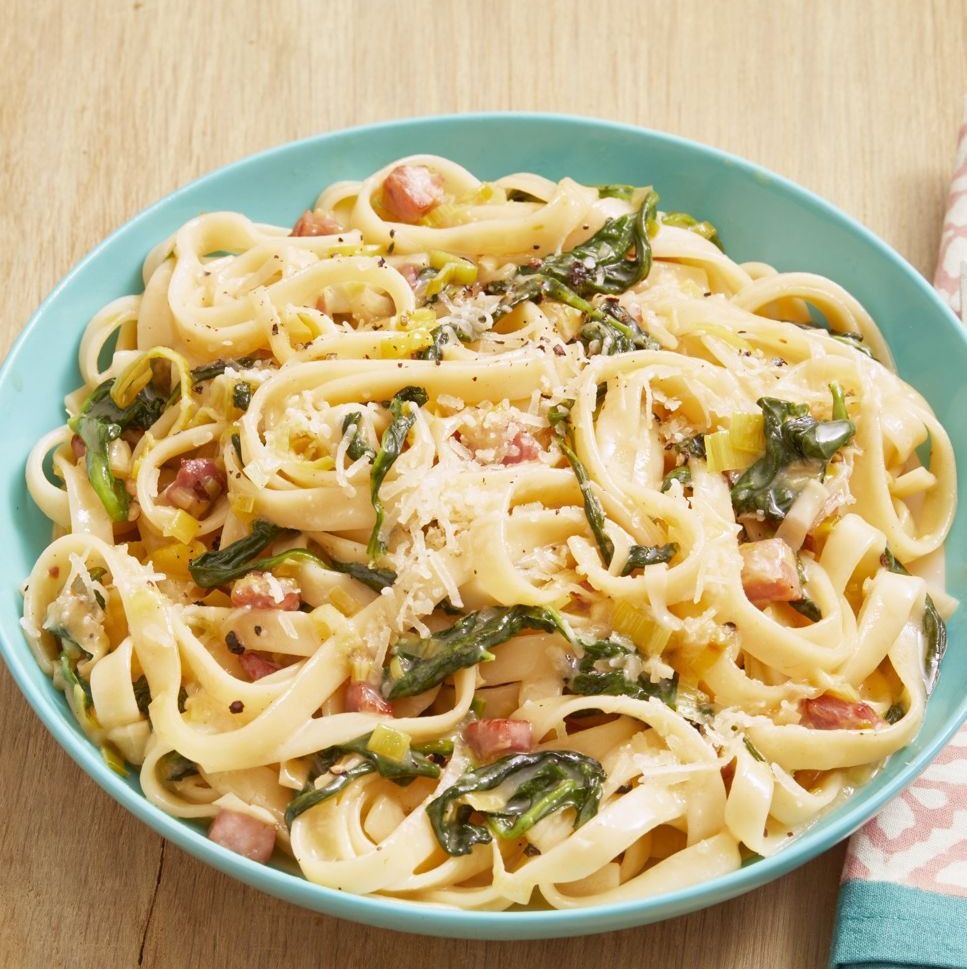 pasta with ham leeks and spinach on wood surface