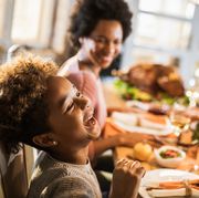 family laughing at the dinner table while eating their thanksgiving meal