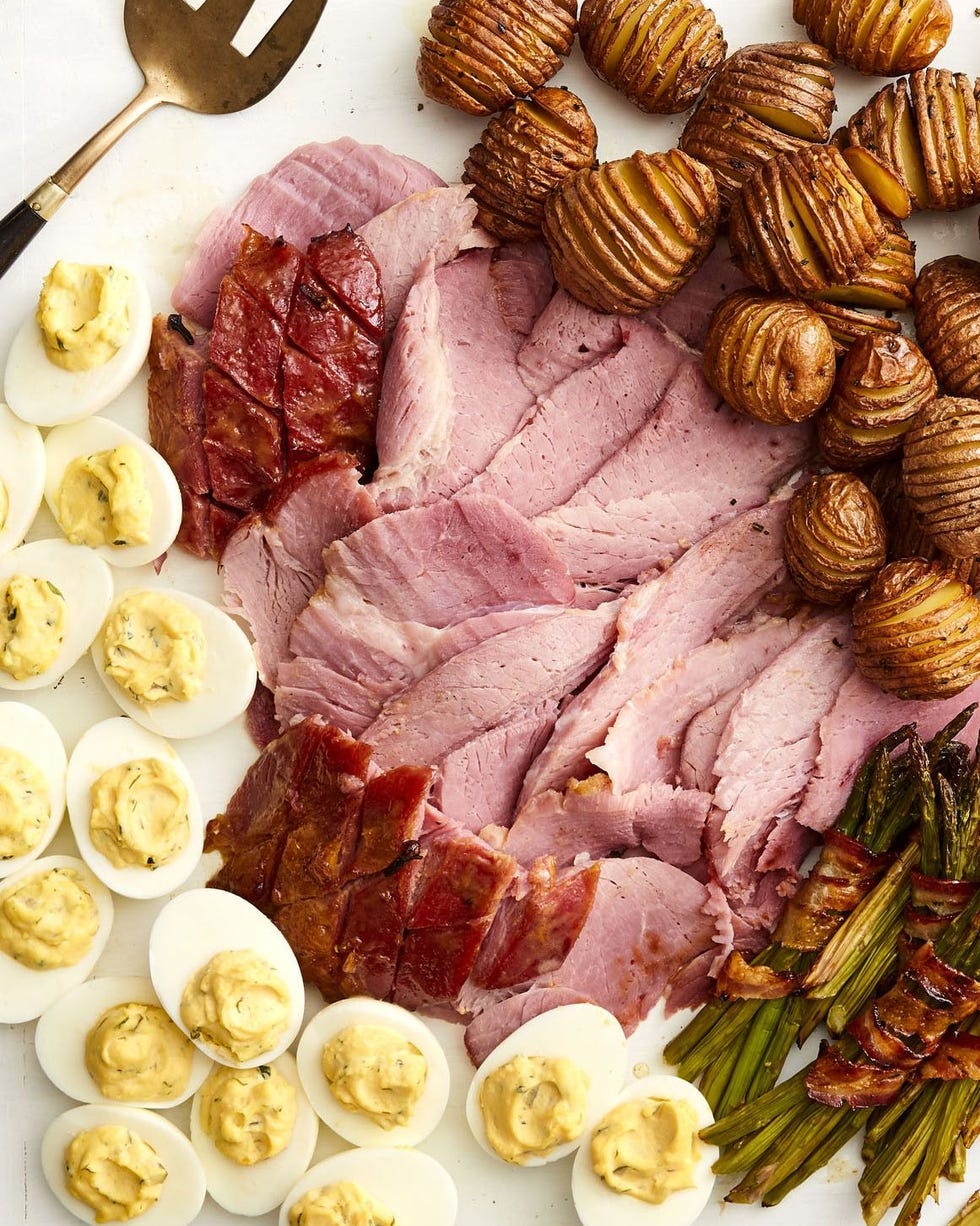 honey mustard glazed ham sliced on platter with eggs potatoes and asparagus