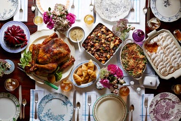 the table features a large, beautifully roasted turkey garnished with greens and lemon slices in the center