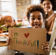 thanksgiving quotes  child holding up a handwritten sign at the dinner table reading i'm thankful