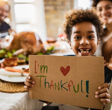 thanksgiving quotes  child holding up a handwritten sign at the dinner table reading i'm thankful