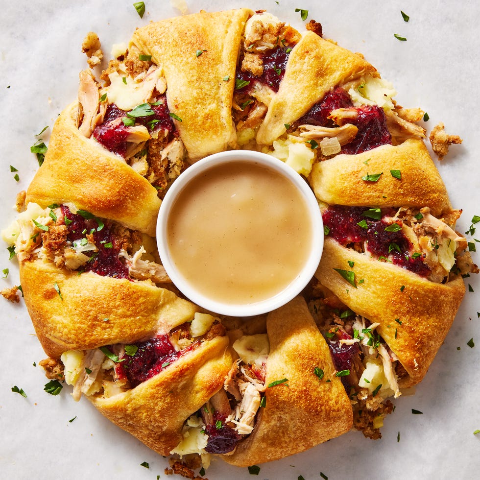 a ring of crescent dough surrounding traditional thanksgiving leftover ingredients like cranberry sauce and stuffing