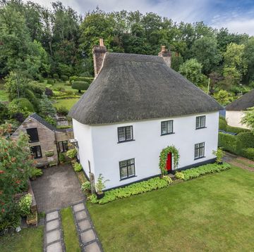 thatched cottage with a white exterior is up for sale in a quaint dorset village