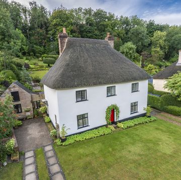 thatched cottage with a white exterior is up for sale in a quaint dorset village