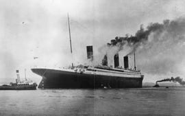 a black and white photo of the titanic next to smaller boats in the water