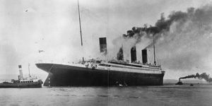 a black and white photo of the titanic next to smaller boats in the water