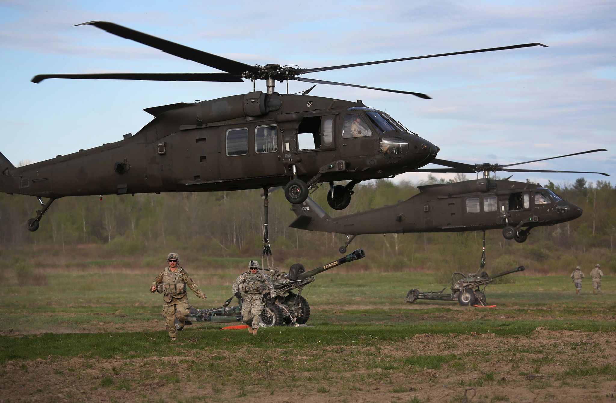 10th mountain troops train with black helicopters and 105 millimeter howitzers