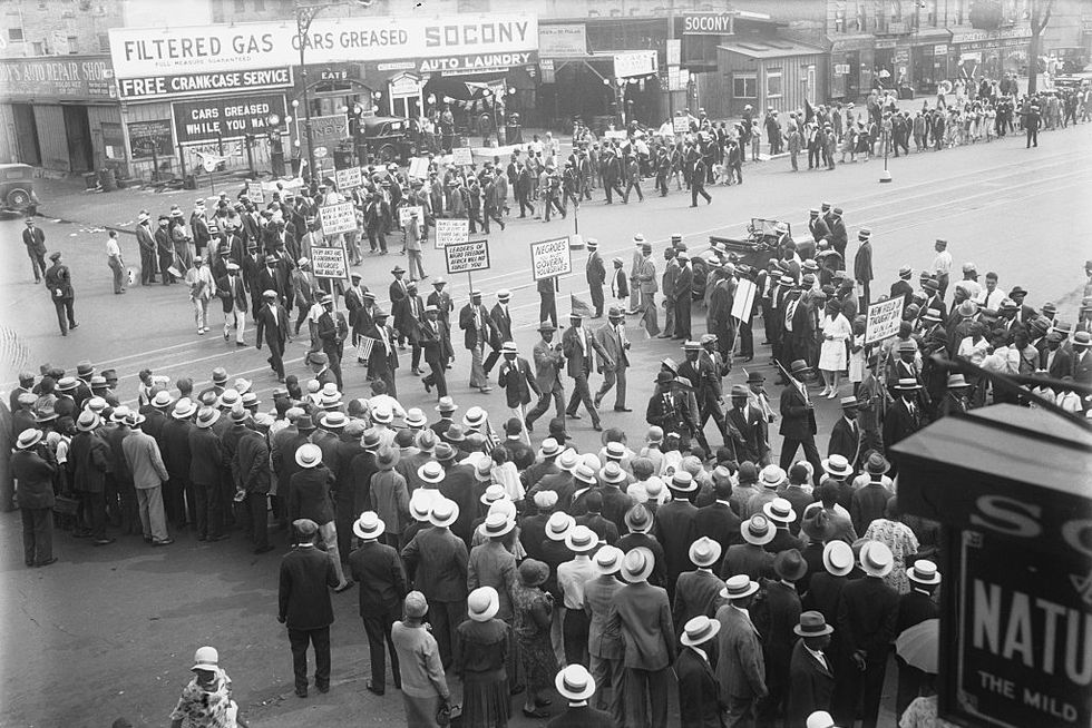 a crowd watches as many people walk in a parade holding signs