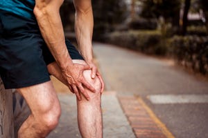 the athlete holds on to his knee as he feels pain