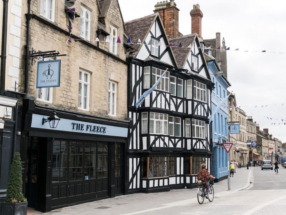 a person riding a bicycle down a street with john knox house in the background