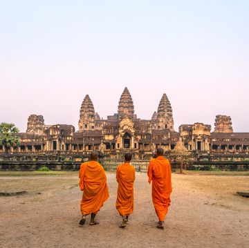 three buddhist monks walking to angkor wat temple, at sunrise siem reap, cambodia
