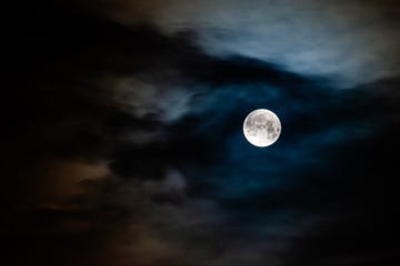 the blue moon is seen between some clouds in the sky