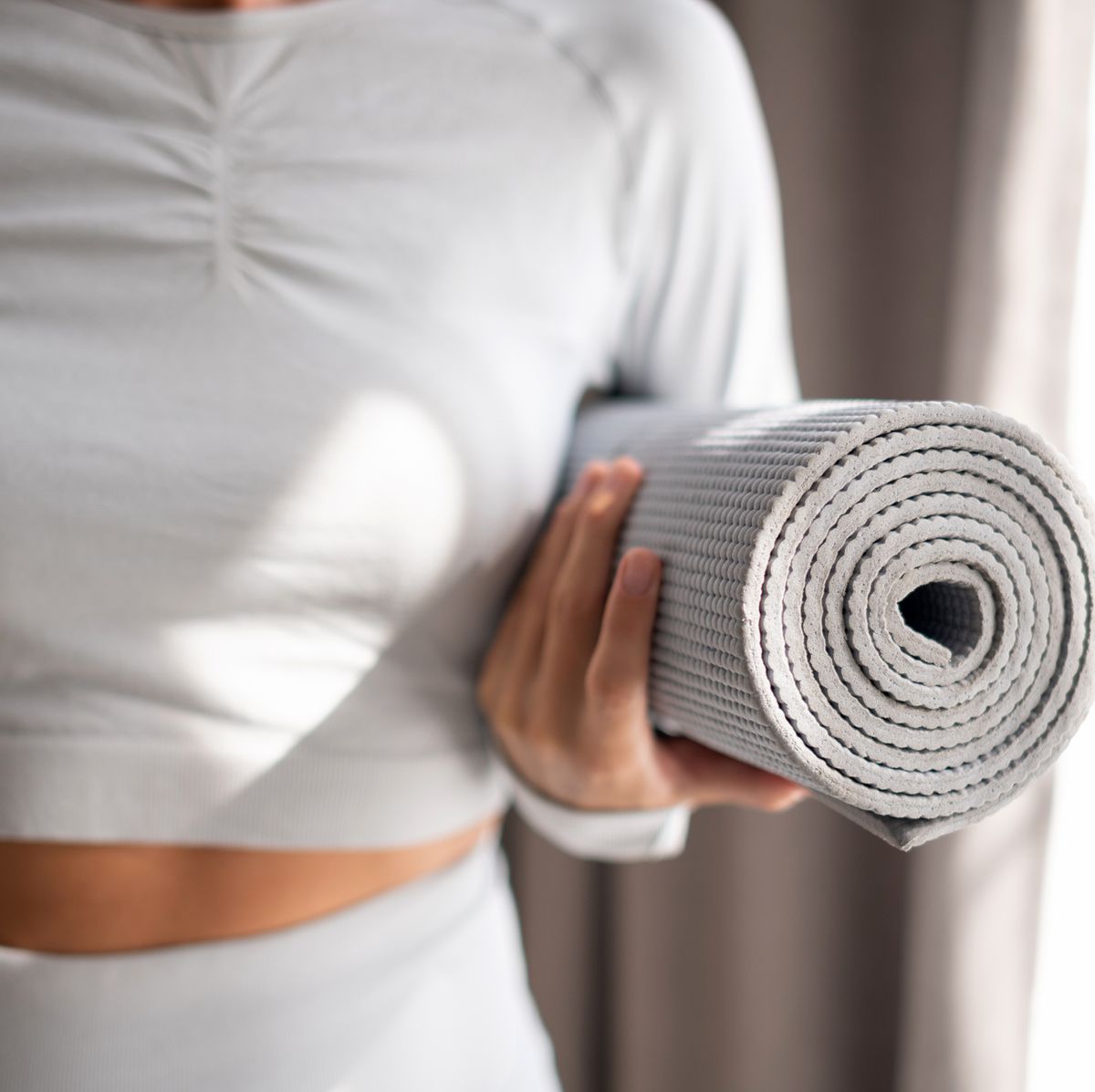 https://hips.hearstapps.com/hmg-prod/images/the-body-of-a-slender-girl-holds-a-yoga-mat-in-her-royalty-free-image-1695218867.jpg?crop=0.668xw:1.00xh;0.181xw,0&resize=1200:*