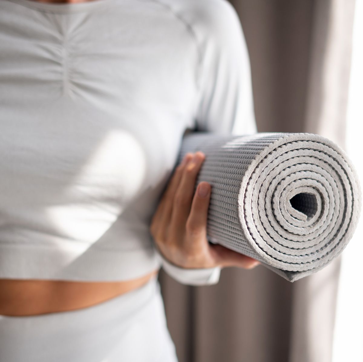 https://hips.hearstapps.com/hmg-prod/images/the-body-of-a-slender-girl-holds-a-yoga-mat-in-her-royalty-free-image-1695218867.jpg?crop=0.668xw:1.00xh;0.181xw,0&resize=1200:*