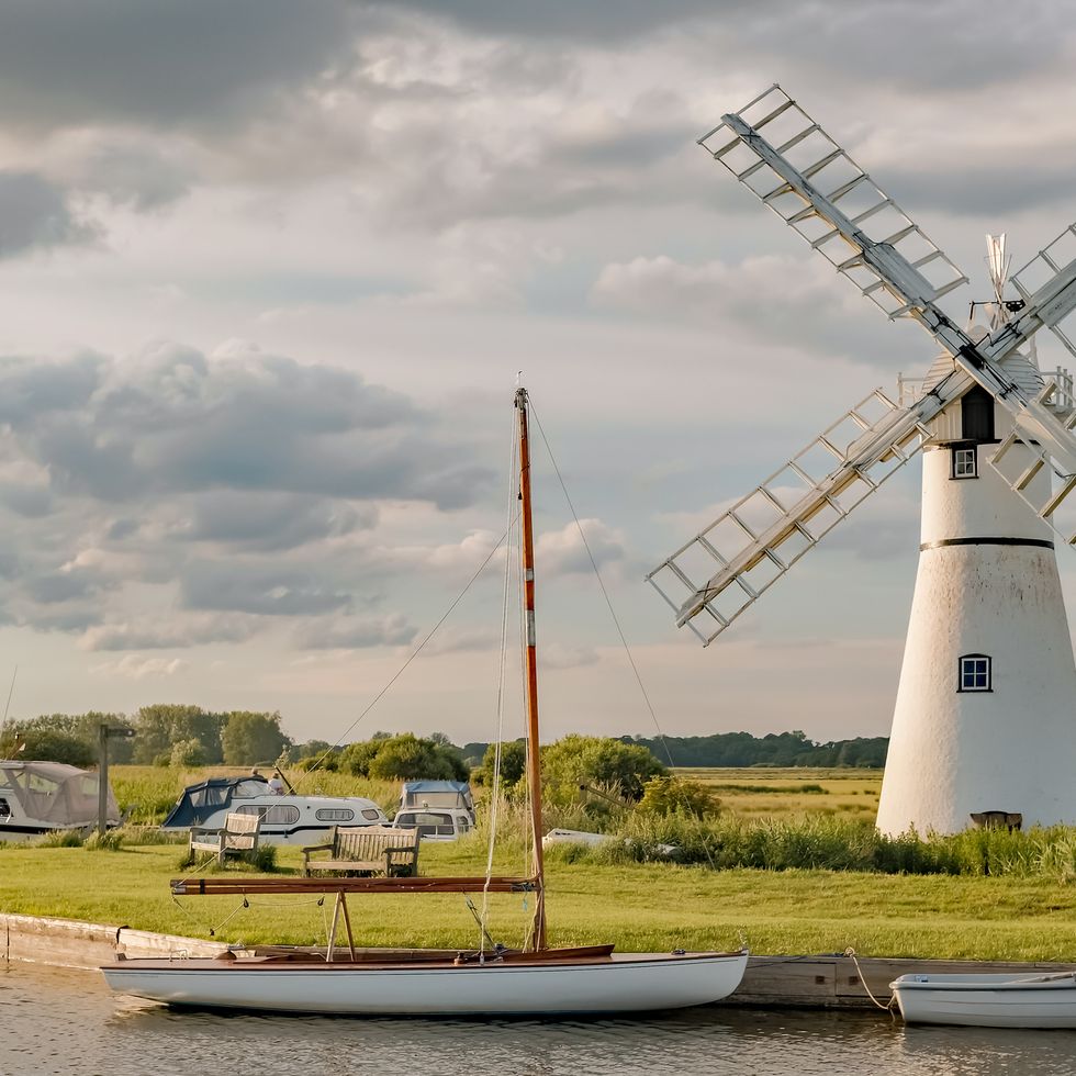 thurne mill on the waterside of thurne river mouth in the norfolk broads national park on a cloudy summers evening