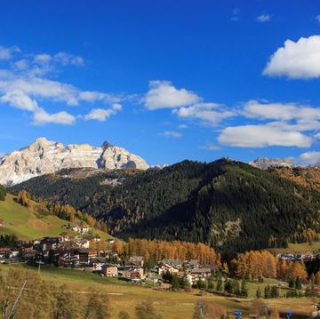 The colorful woods frame the village and the high peaks in autumn Gardena Valley. Trentino-Alto Adige. Italy. Europe