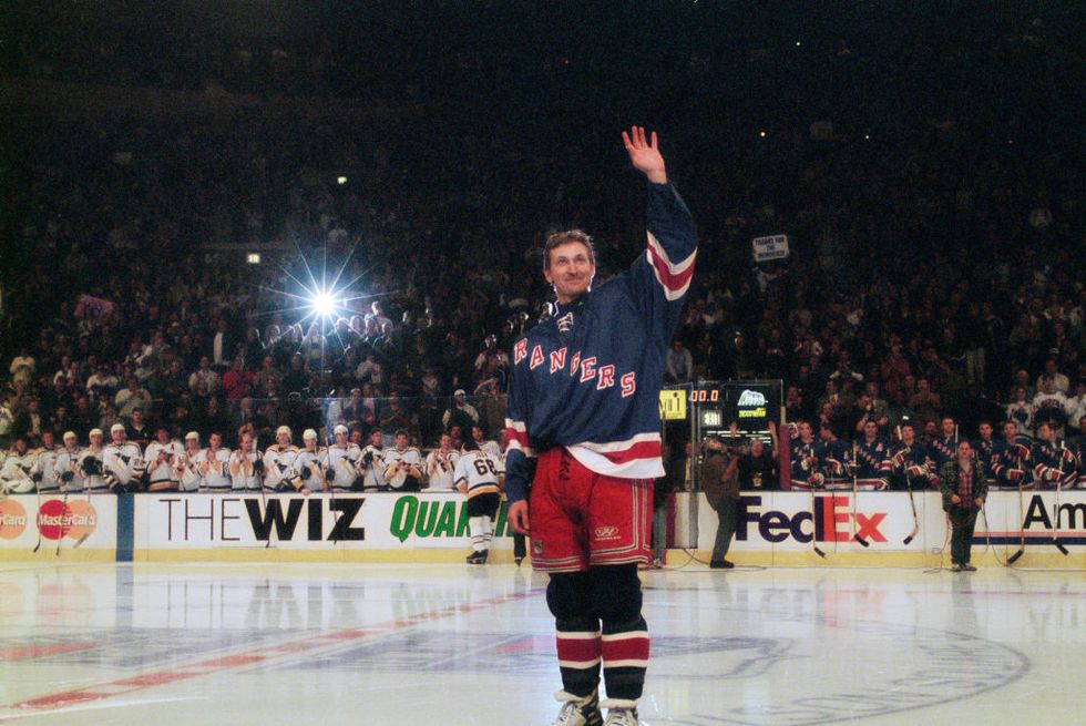 wayne gretzky stands on an ice rink and waves at the crowd