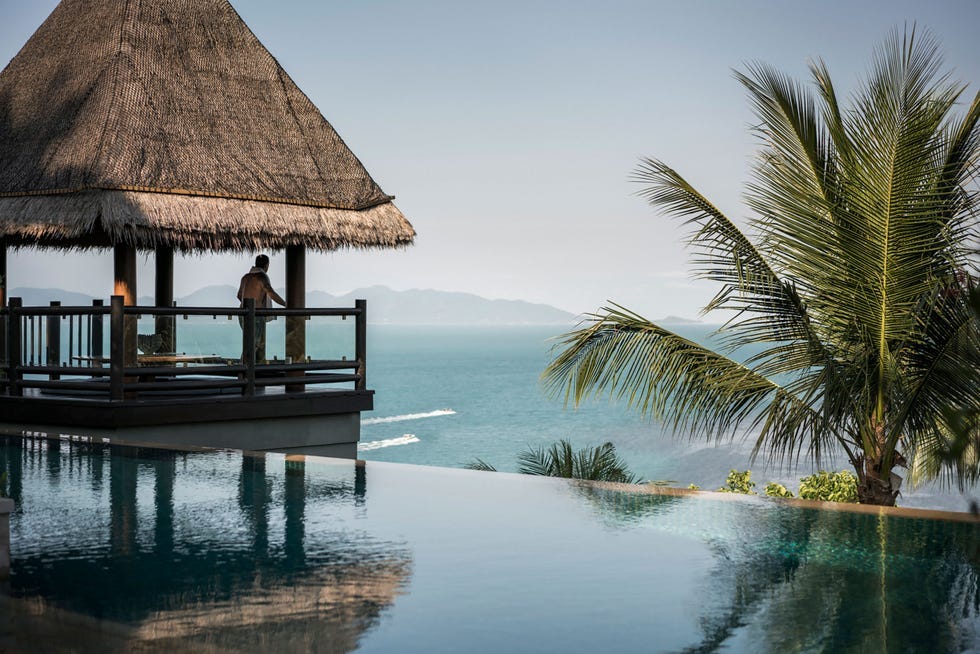 seaside view from a villa with a person standing on a deck and palm trees