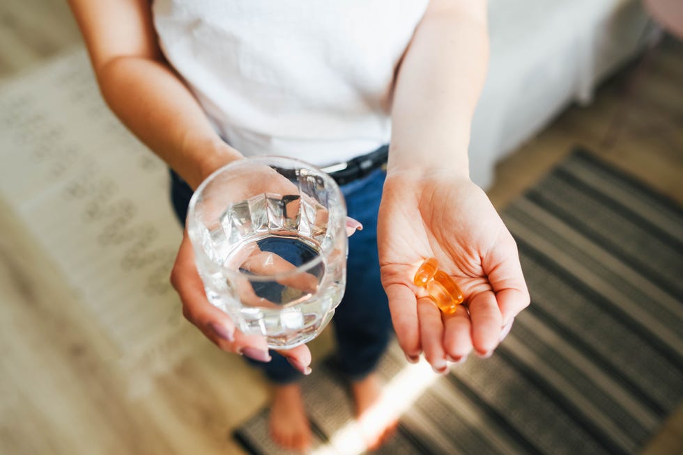 the girl holds vitamins and a glass of water in her hand morning rituals water glass of water water balance in the body vitamins vitamins and dietary supplements