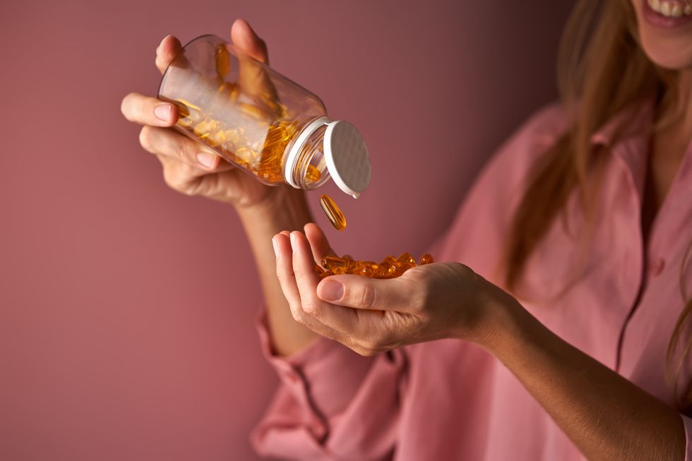 the girl in pink pours omega capsules into her palm