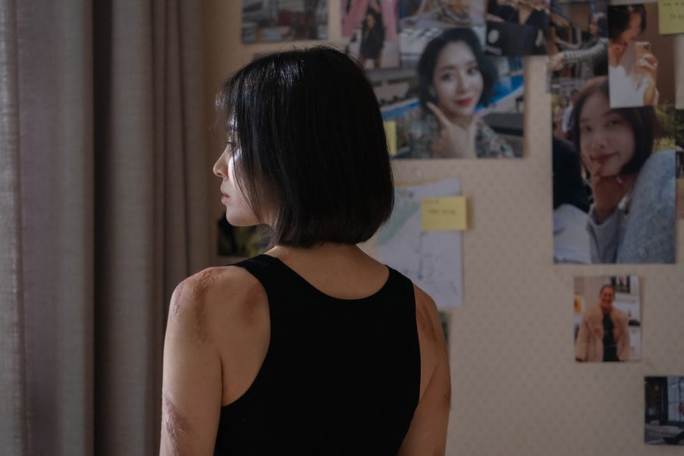 a woman with her back to the camera has visible burn scars from her childhood bullies in a scene from korean drama the glory