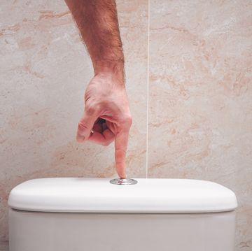 The hand presses the button on the toilet bowl, the economical drain