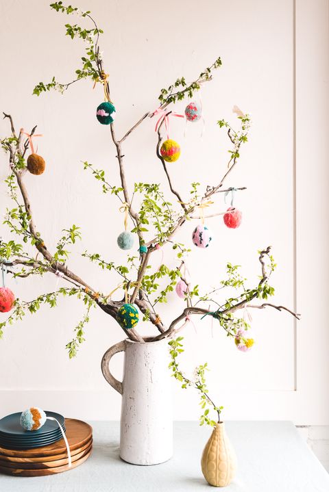 easter egg tree with solid color, dotted and striped eggs made out of yarn hanging off of spring branches