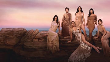 group of women in elegant flowing dresses posing on rocks at sunset