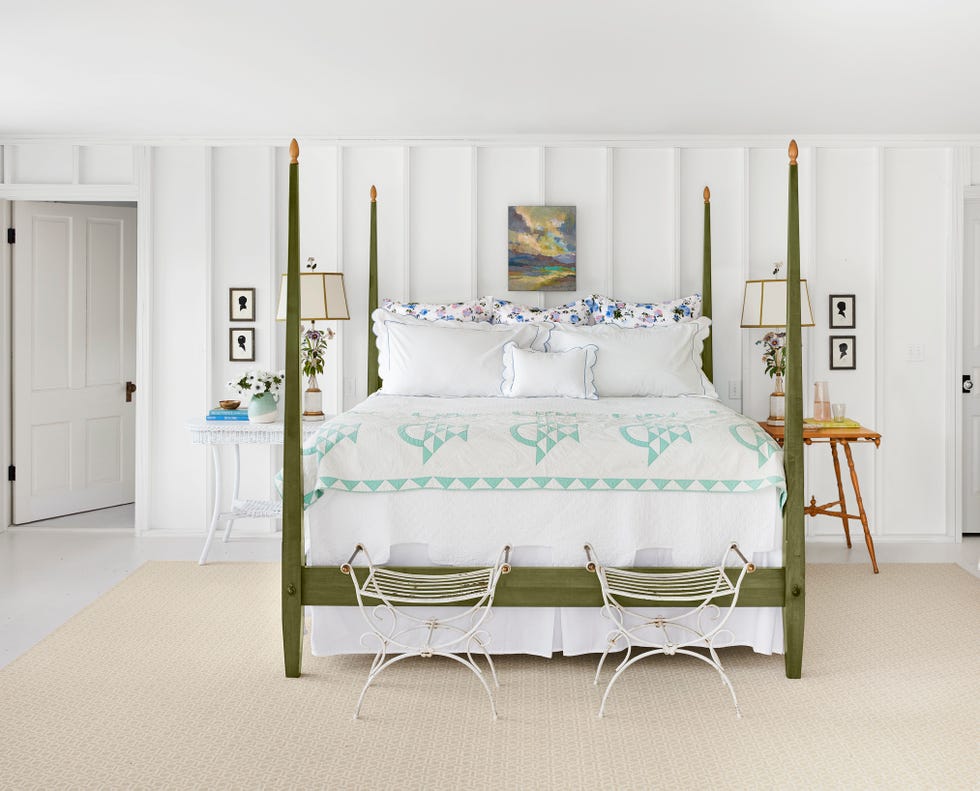 a white bedroom with a green pencil post bed