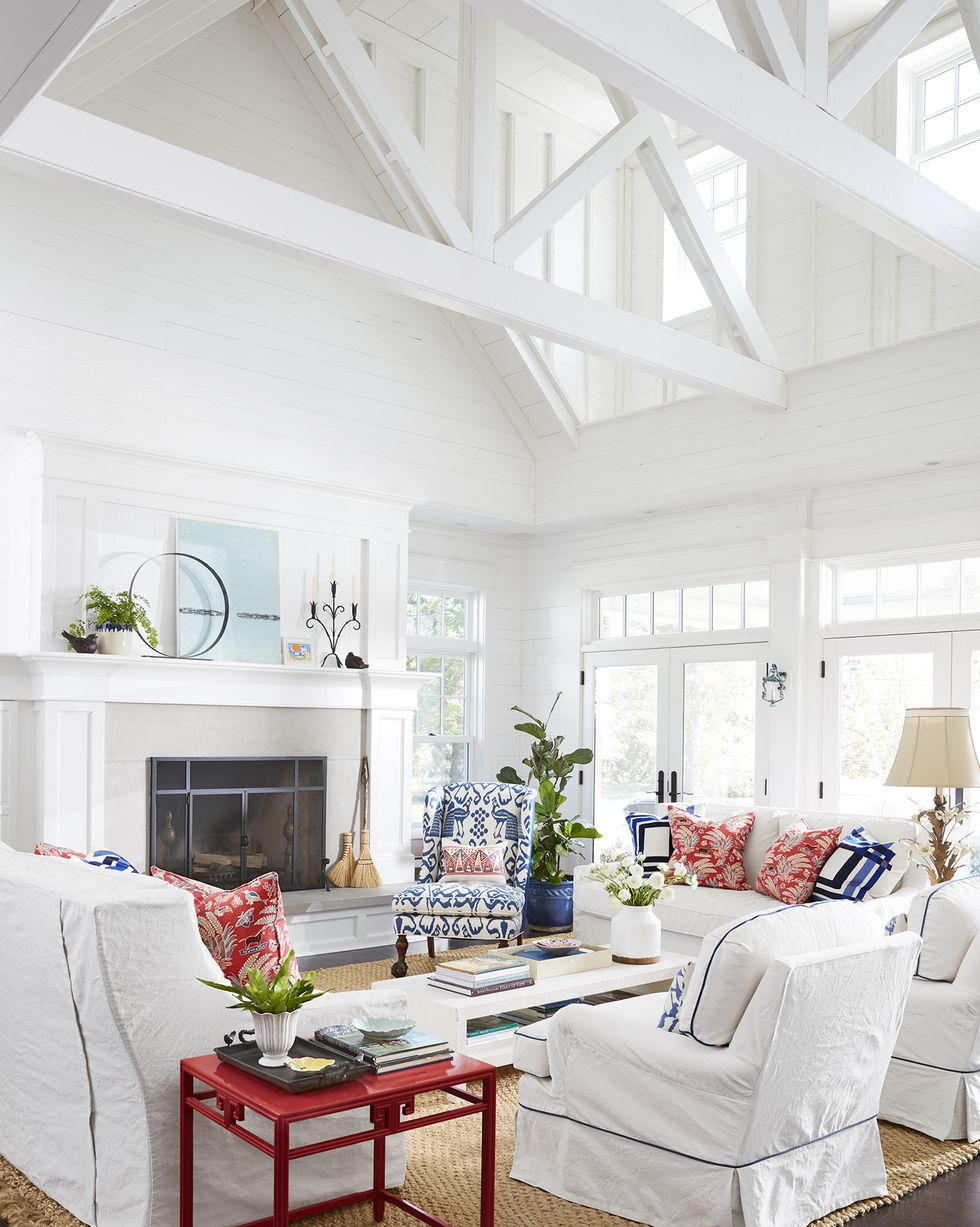 two story all white living room with white slipcovered upholstery with blue and red pillows