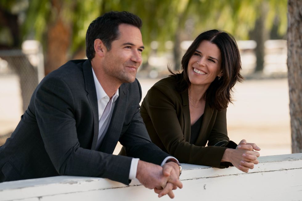 the two characters, who are ex husband and wife in the series, leaning over a wall outdoors, smiling, talking