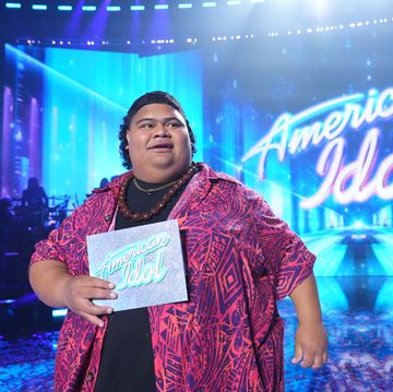 iam tongi looking off camera as he holds the winner envelope on the american idol stage