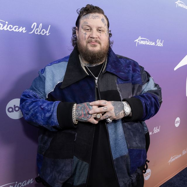 jelly roll crossing his hands while smiling for a photo in front of an american idol backdrop