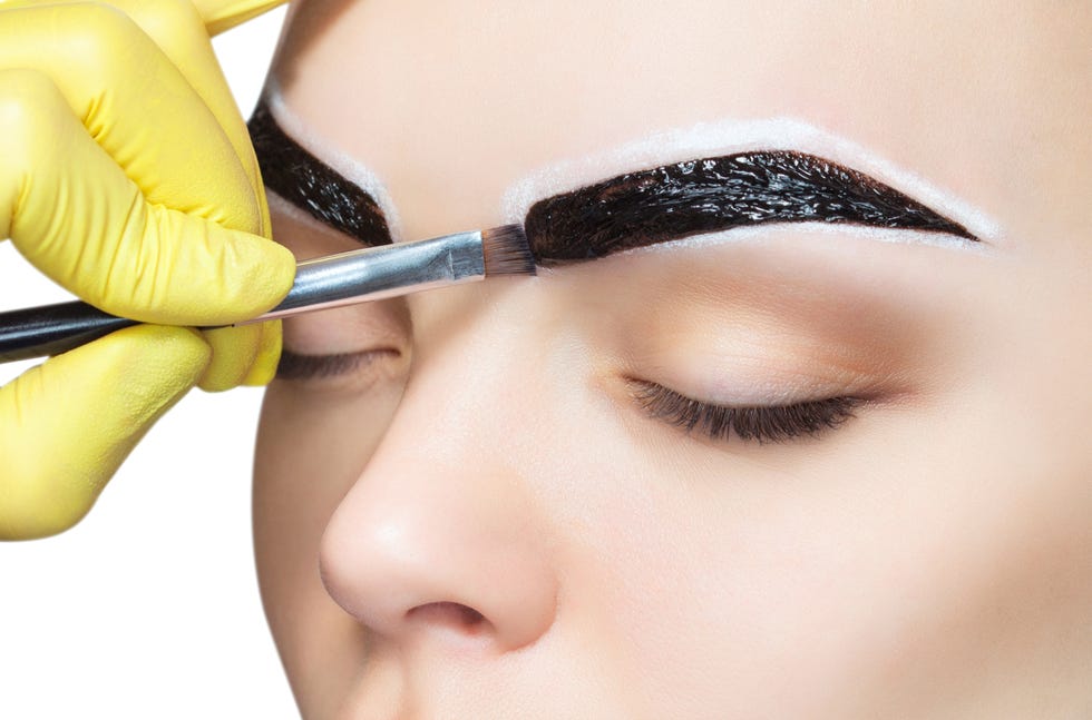 The make-up artist applies a paints eyebrow dye on the eyebrows of a young girl. Professional face care.