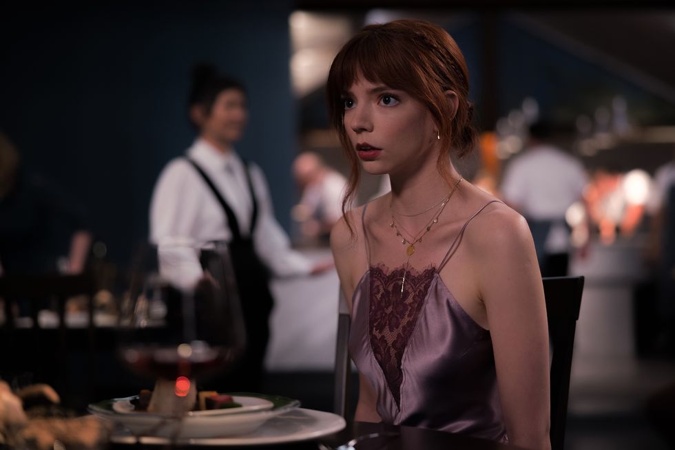 film still from the menu, featuring anya taylor joy as margot sitting at a dinner table in a high end restaurant