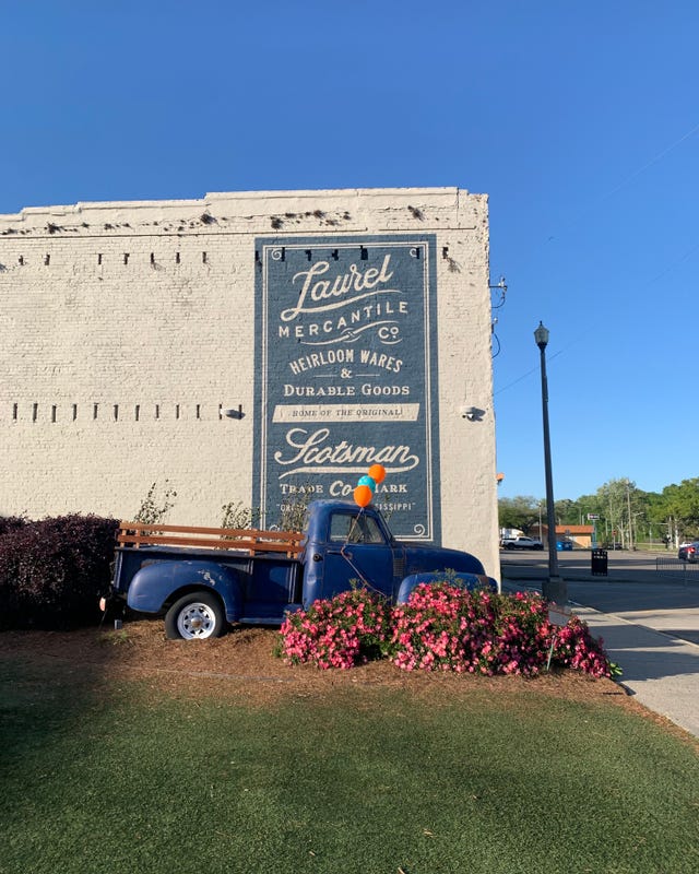 mural on a building featuring vintage branding and a classic blue pickup truck adorned with balloons