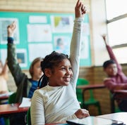 Happy, confident kid raising her hand in class in a story about self-advocacy happy, confident kid raising her hand in class in a story about self advocacy
